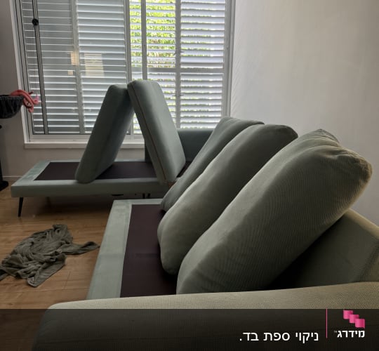 ספות עם כריות מונחות ליד חלון עם תריסים
